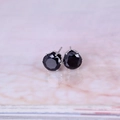 Nahaufnahme von 8mm runden schwarzen Zirkonia-Ohrsteckern mit silberner 6-Krallen-Fassung - Silber & Schwarz