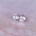 Klassische 8mm Zirkonia-Ohrstecker mit silberner 6-Krallen-Fassung auf Marmorboden - Silber + Weiß