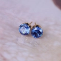 Detail of 8mm round blue zircon stud earrings with classic gold six-prong setting - Gold + Blue