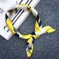 Elegant yellow silk scarf with blue and white floral prints tied over a magazine - Yellow White Figure