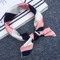 Silk neck scarf with pink and navy blue stripes tied in a bow on textured fabric - Korean Pink