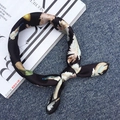 Silk square scarf with feather print in black finish placed on a fashion magazine - Black Feather