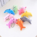 Ensemble de huit porte-clés dauphins en peluche colorés disposés en cercle sur fond blanc - Couleurs Assorties Aléatoires / 8cm
