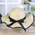 Detailed view of beige straw sun hat with wide brim and elegant black ribbon bow tie - Beige
