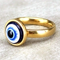 Golden stainless steel evil eye ring with blue enamel inlay on a grey textured background - US 10 / Gold