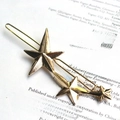 Golden star hair clip with three graduated pentagons on a magazine background - Star / Gold