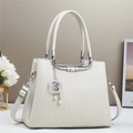 White structured handbag with vertical stripes and star pearl charm on a stylish table - Off White