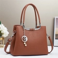Detailed close-up of brown textured leather handbag with silver star and moon charm - Earthy Yellow