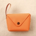 Detail of vibrant orange leather coin purse with bronze snap button on burlap background - Orange