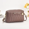 Textured mauve crossbody camera bag with gold hardware in a stylish lifestyle setting - Purple