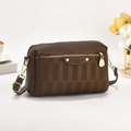 Detail of dark brown leather crossbody bag with lychee texture and gold metal hardware - Coffee