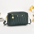 Macro detail of dark green pebbled leather handbag with gold zipper and metal plate - Green