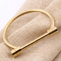 Polished golden stainless steel horseshoe bangle with D-shape screw clasp on linen cloth - Gold