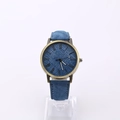 Blue denim texture watch with bronze case and Roman numerals on transparent stand - Blue