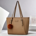 Detalle de bolso tote marrón de piel litchi con hebilla dorada y pompón decorativo - Caqui