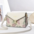 Chic cream crossbody bag with floral embroidery and gold hardware on white stand - White