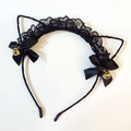 Detail von schwarzen Katzenohren aus Spitze mit Schleifen und goldenen Glöckchen - Schwarz