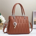 Detailansicht braune Handtasche mit geometrischer Textur, Silberbeschlägen und Perlenanhänger - Erdgelb