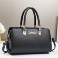 Detail of black lychee grain leather handbag with gold hardware and dual round handles - Black