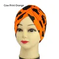 Elastic turban headwrap featuring orange and black cow print with front knot design - One Size / Orange Cow Print