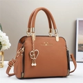 Detailed macro of brown lychee grain PU handbag with gold heart and pearl charm - Earthy Yellow