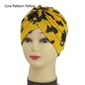 Elastic cotton turban hat featuring a yellow cow print pattern with twist knot detail - One Size / Yellow Cow Print
