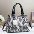 Chic snake print quilted shoulder bag with contrast black handles and plush white charm - Black