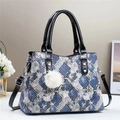 Detail van de tote bag met slangenprint, laklederen bies en zachte pluche pompon - Blauw