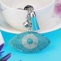 Détail du porte-clés Œil Mauvais avec strass bleus, pompon doux et breloque clochette - Bleu lac