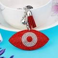 Red evil eye rhinestone keychain with suede tassel and silver bell on blue background - Red