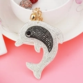 Detailed close-up of a rhinestone dolphin keychain with gold bell and lobster clasp - White
