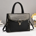 Detailed view of crocodile pattern texture and golden hardware on the black tote bag - Black