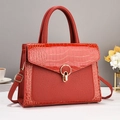 Detail of red crocodile texture tote bag featuring golden circular metal lock and dual leather - Red