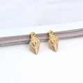 Macro shot of two golden shell-shaped metal charms with polished alloy texture - White Conch