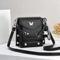 Black minimalist square crossbody bag with butterfly buckle and bear charm on white stand - Black