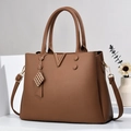 Brown litchi grain leather handbag with V-shaped metal accent and gold pendant charm - Brown
