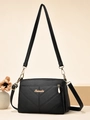 Détail du cuir noir grainé avec coutures en V et logo métallique doré sur le sac à main - Noir