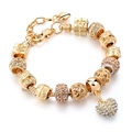 Close-up of golden charm bracelet with crystal heart pendant and diverse decorative beads - PD0018-F