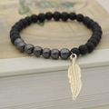 Pulsera de cuentas de hematita negra mate con colgante de hoja dorada sobre libro - Colgante Pluma Dorado / Dorado
