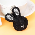 Close-up of black rabbit keychain with crystal rhinestones on white ceramic cup - Black