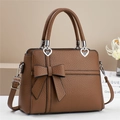 Détail du sac à main en cuir grainé marron avec nœud décoratif et boucle en cœur - Marron