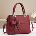 Détail d'un sac à main bordeaux avec boucles en forme de cœur et nœud élégant - Rouge