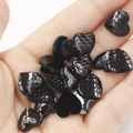 Macro shot of 12mm black heart-shaped resin charms with fish scale texture on palm - 12mm Black Iridescent