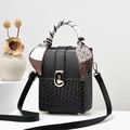 Detail van zwarte lederen crossbody tas met geweven textuur en decoratieve zijden sjaal - Zwart