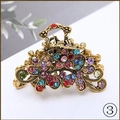 Vintage gold flower hair claw clip with multi-colored rhinestones on white surface - Rainbow