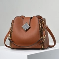 Detail der braunen Eimer-Tasche aus Leder mit Narbung und goldenem Metallverschluss - Erdgelb
