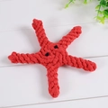 Starfish shaped red cotton rope chew toy for dogs with a white wood grain background - Starfish