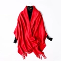 Chic red wool knit scarf with fringe tassels shown on a black turtleneck display - Red