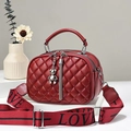 Close-up of a quilted burgundy crossbody bag with a silver bear charm and tassel details - Wine Red