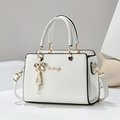Detail of white cross-grain leather handbag with gold logo and pearl bow charm - White